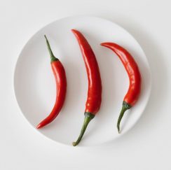 three cayenne peppers on a white saucer